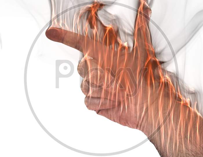 A human hand on fire burning with orange flames and some smoke in front of a white background