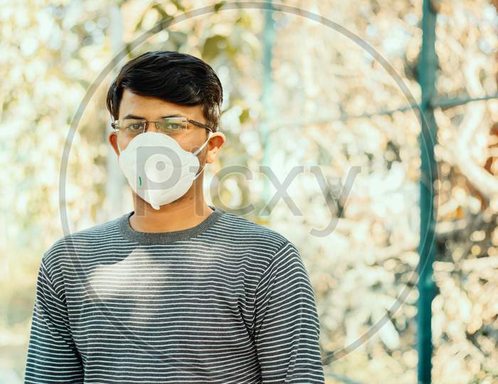 Asian Man Wearing The N95 Medical Face Mask Due To Coronavirus Or Covid-19 Outbreak, Outdoor - Person Protecting From Air Contamination, Coronavirus, Sars Cov 2 Or Viral Infection By Wearing Mask.
