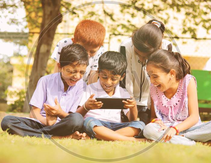 Group of Children using a Mobile or Smartphone in a Park or Outdoors