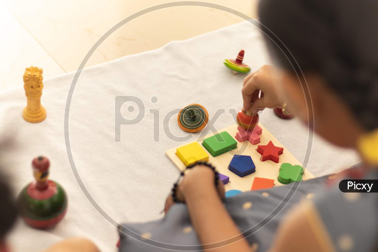Focus On Hands Of Cute Little Child Girl Playing With Indian Wooden Channapatna Toys In The Room