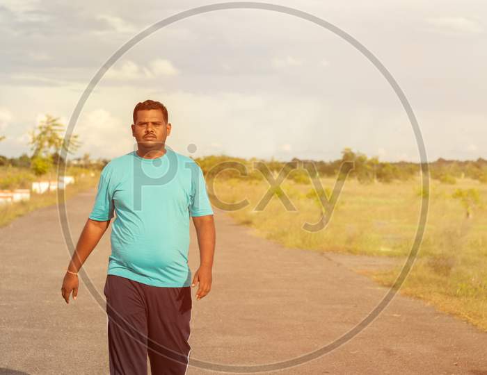 Overweight Man Running On Road - Concept Of Fat Man Fitness - Obese Person Jogging To Reduce The Weight.