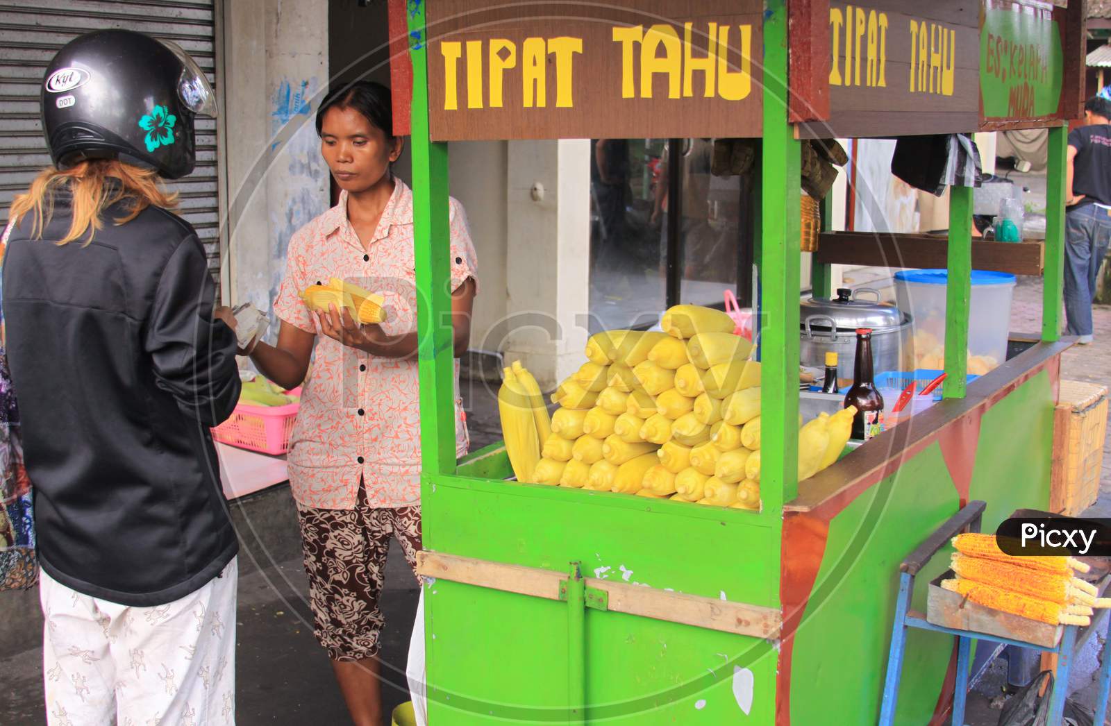 Tourist Bargaining With Street Steamed Corn Seller