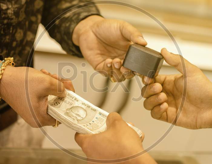 Close Up Of Hands Buying Or Purchasing Gold Jewellery By Paying Indian Currency At Jewelry Shop India - Concept Of Gold Investment For Profit