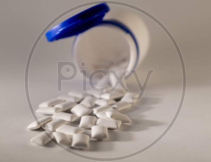 Gums scattered from bottle on a white background.