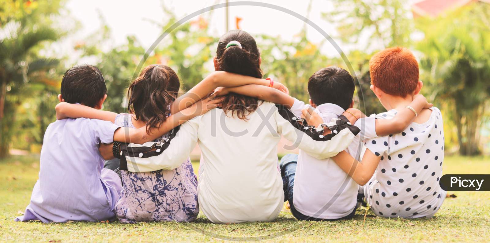 Back View, Group Of Kindergarten Multi Ethnic Kids Friends Arm Around Sitting Together At Park Outdoor - Concept Showing Of Childhood Friendship, Togetherness With Diversities.