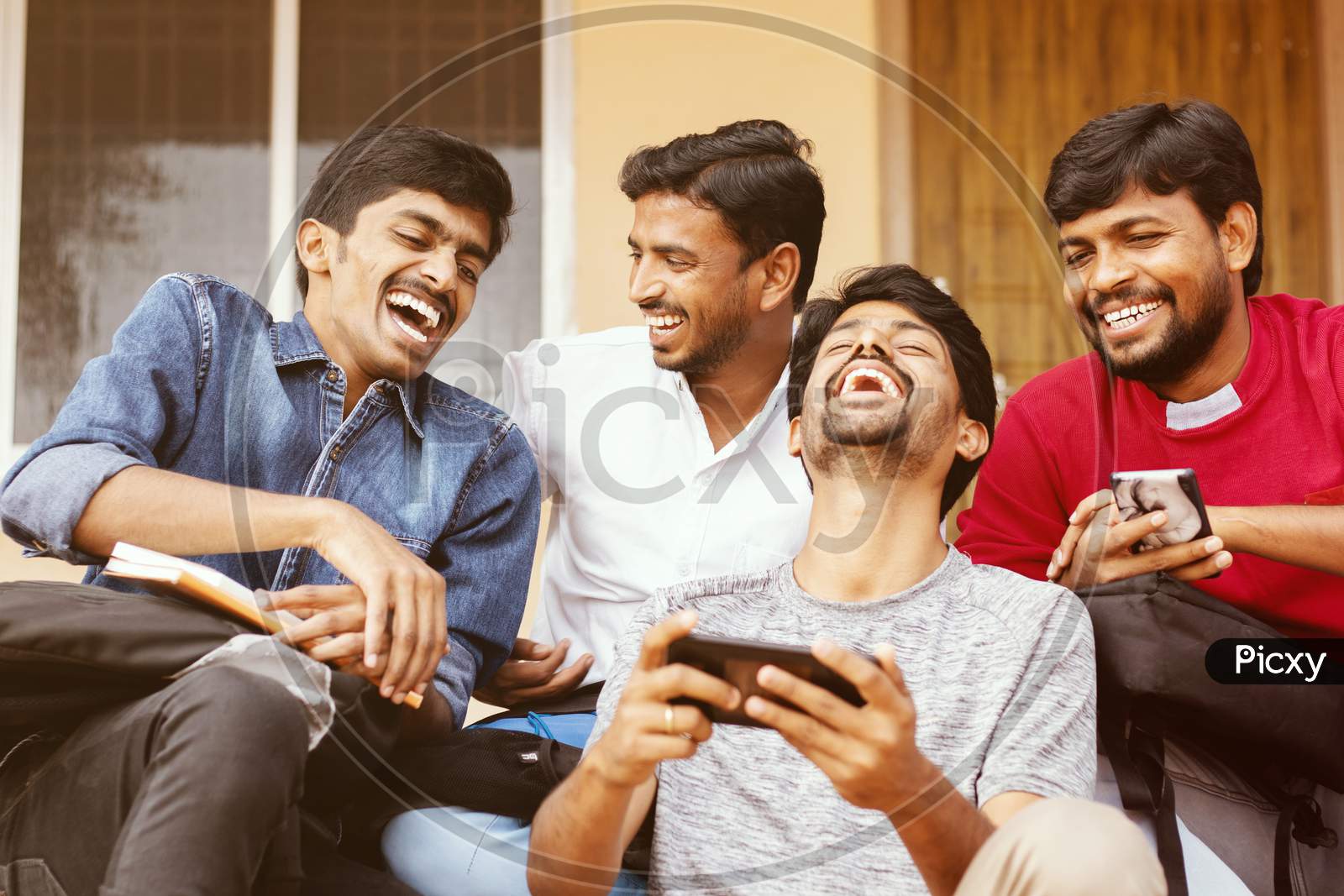 Group Of Happy Young College Students By Looking At Mobile Phone Laughing Loudly At University Campus - Millennials Enjoying Online Video Content Or Social Media By Watching Smart Phone.