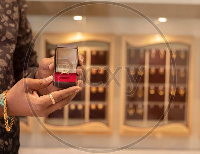 Close Up, Hands Showing Gold Ring with Jewelry Box With Copy Space At Jewellery Store