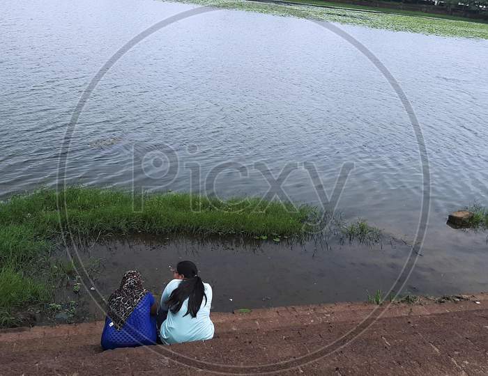 Two Girls sitting on the stairs of the ghat at Bindusagar Pond