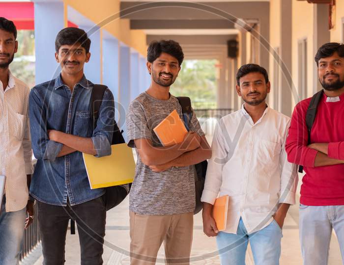 Happy Young Students Holding Books And Standing At College Corridor - Group Of Multiracial Confident Youth At University Campus - Concept Of Friendship, Togetherness And Student Life.