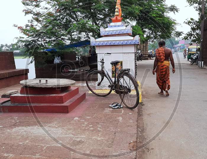 Back side of a Hindu priest walking through the road.