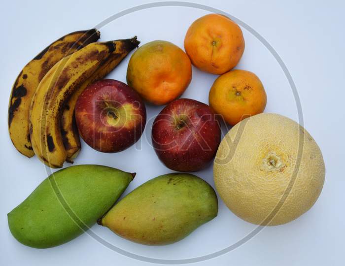 Top view of Muskmelon, Oranges, Mango, Banana And Apple.