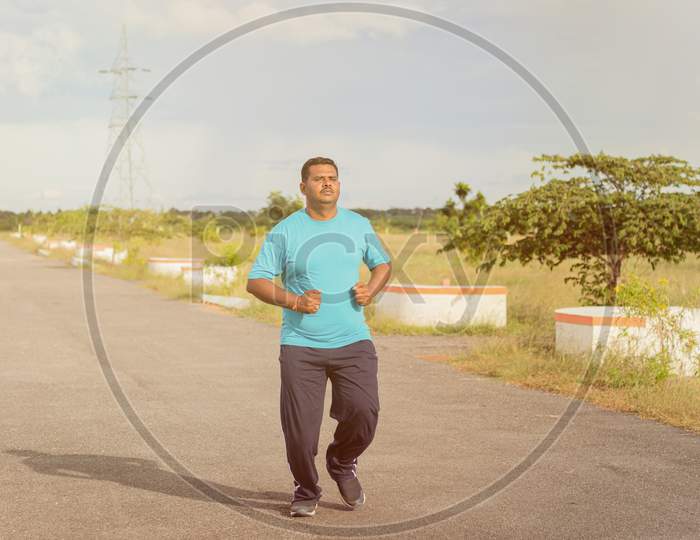 A Young Indian Man Running or Jogging on an Empty road as a Fitness Routine