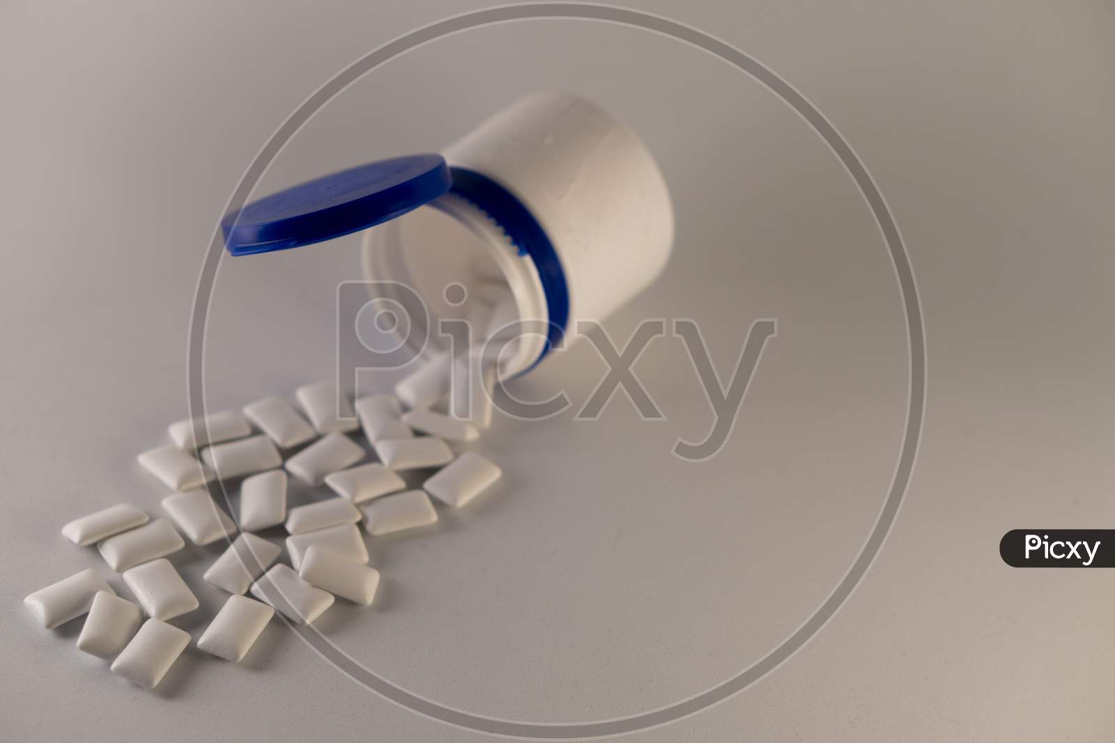 Gums scattered from bottle on a white background.