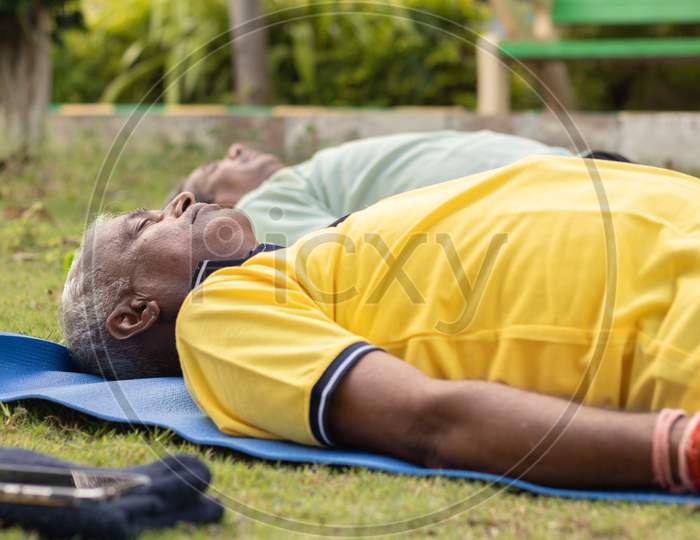 Elderly Man Or Old Man Doing Savasana as part of Fitness Routine At Outdoors