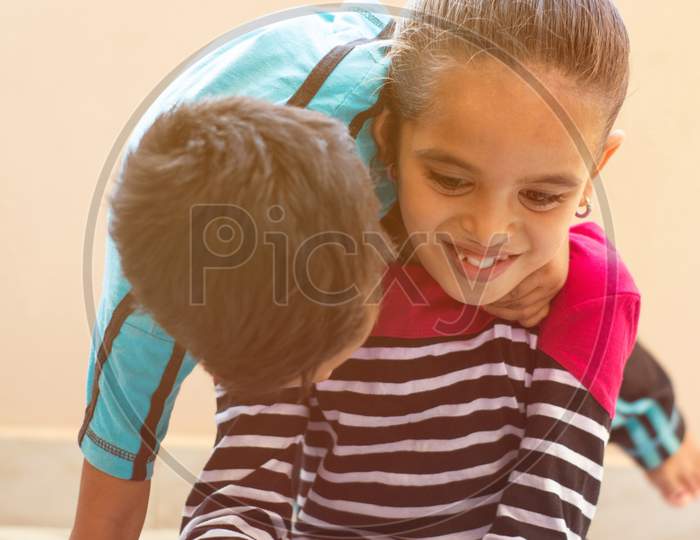 Two Cute Little Indian Kids Having Fun By Watching Mobie Device At Home