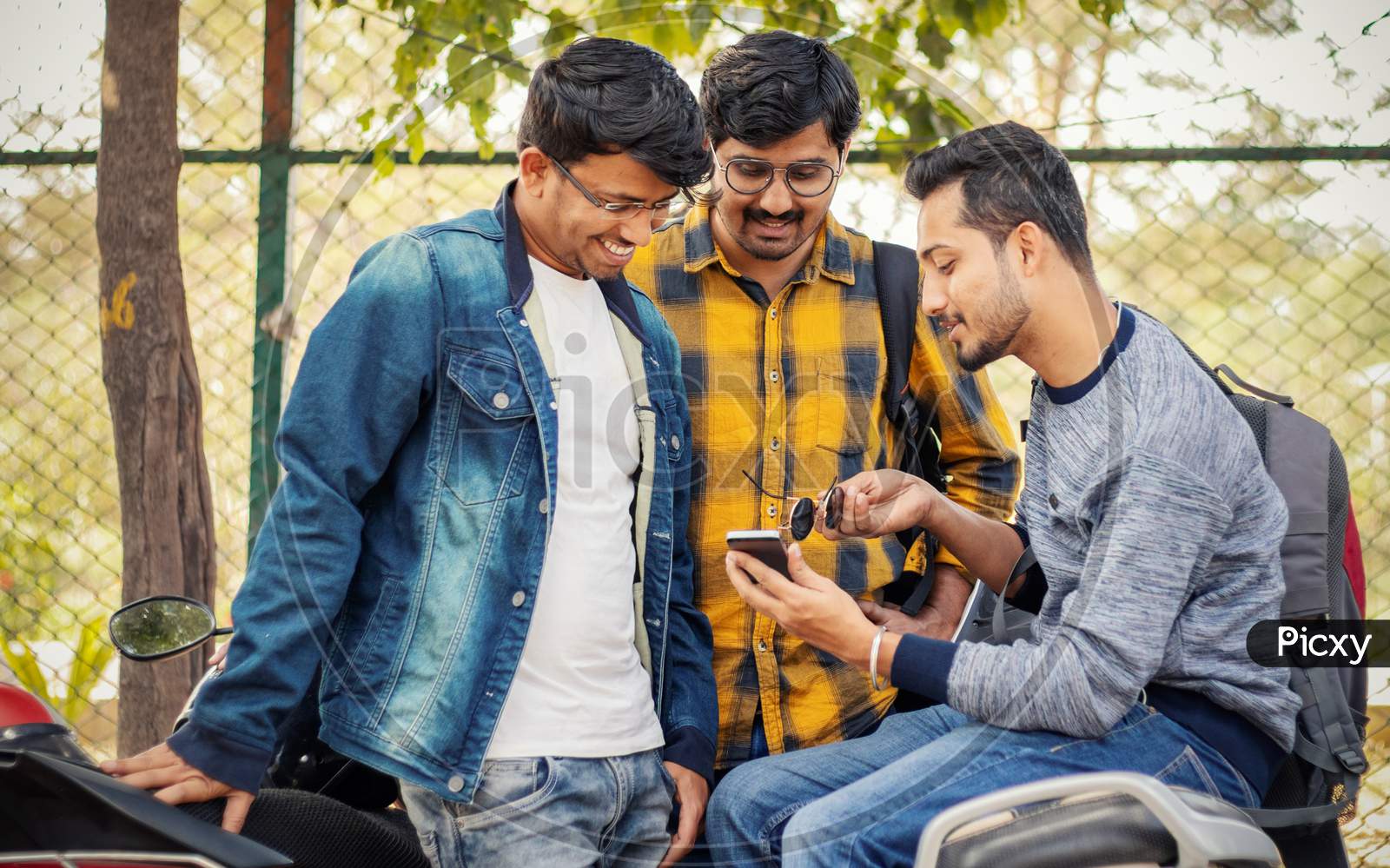 Students Busy On Mobile At College Parking Area On Bike - Young Millennials Busy On Phones And Technology - Concept Of Friendship And Urban Youthful Lifestyle.