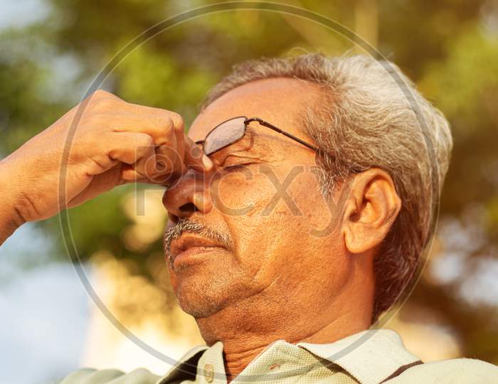 Worried Old Man Sitting at Outdoors With Hand On Forehead In Serious Mood Emotion