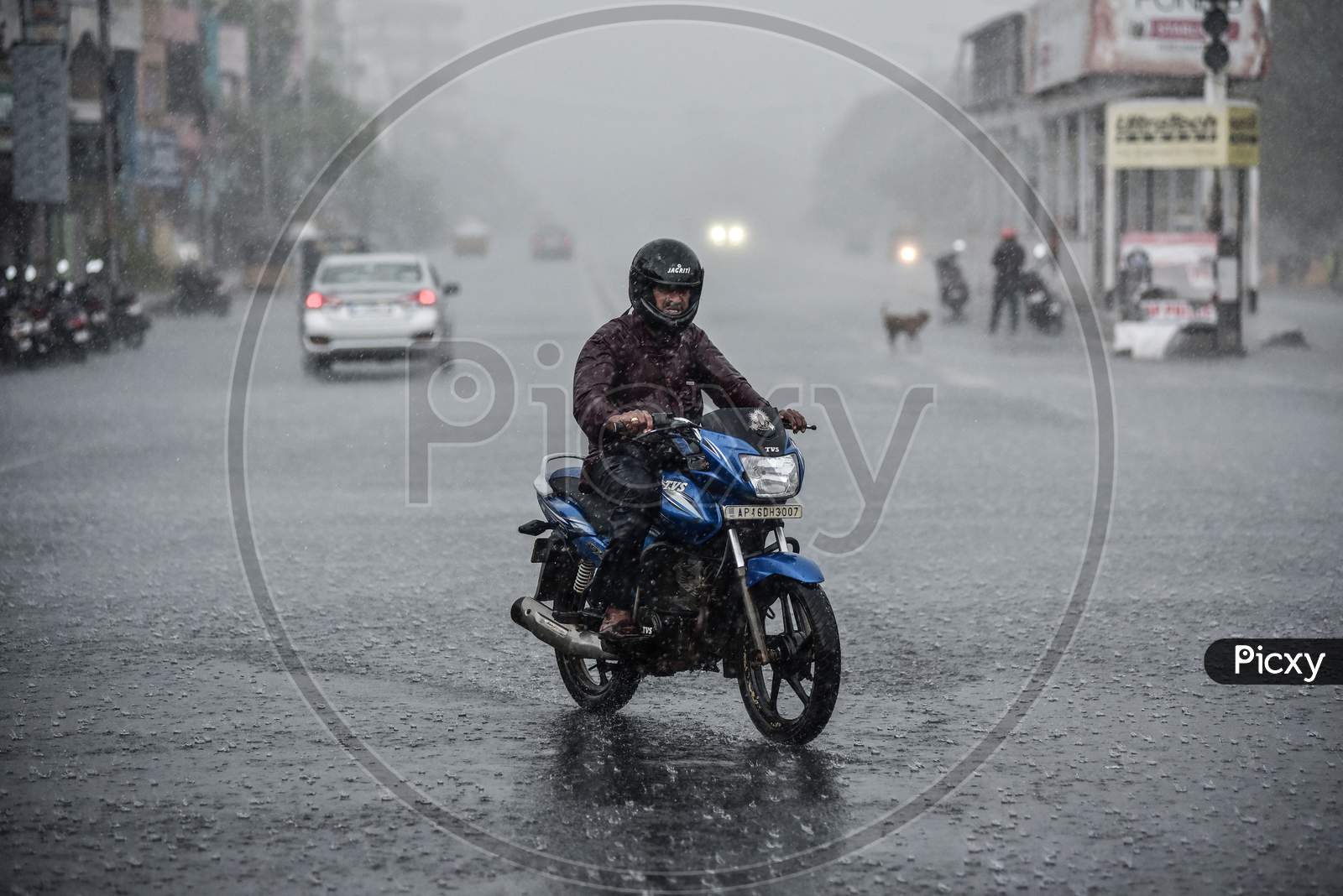 A motorist rides through the rain, during the fifth phase of coronavirus lockdown in Vijayawada.