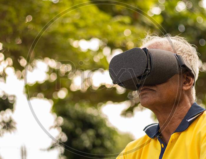 An old man or Elderly man having Virtual Reality Experience at Outdoors