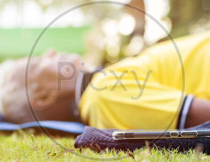 Elderly Man Or Old Man Doing Savasana as part of Fitness Routine At Outdoors