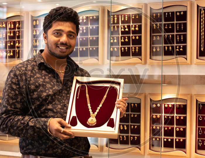 A Happy Young Person Holding A Gold Chain At Jewelry Box With Copy Space At Jewellery Store
