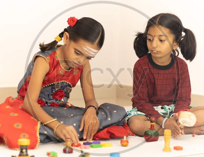 Interactively Two Indian Children Or Little Sisters Happily Playing With Colorful Wooden Toys Inside The Home.