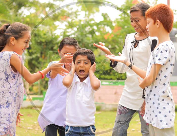 Young Children's Group Pointing Fingers Bullying To Caucasian - Concept Of Racism, Discrimination At School And Outdoors - Screaming Young Kid Feeling Sad By Friends.