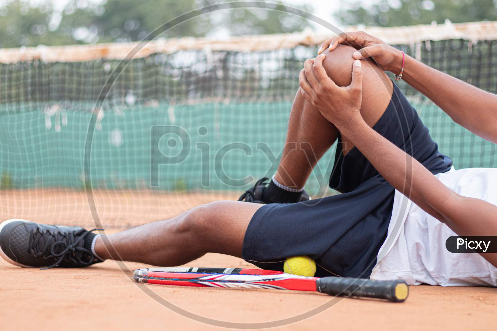 Young Indian Man Holding Knee Due To Pain in a Tennis Court