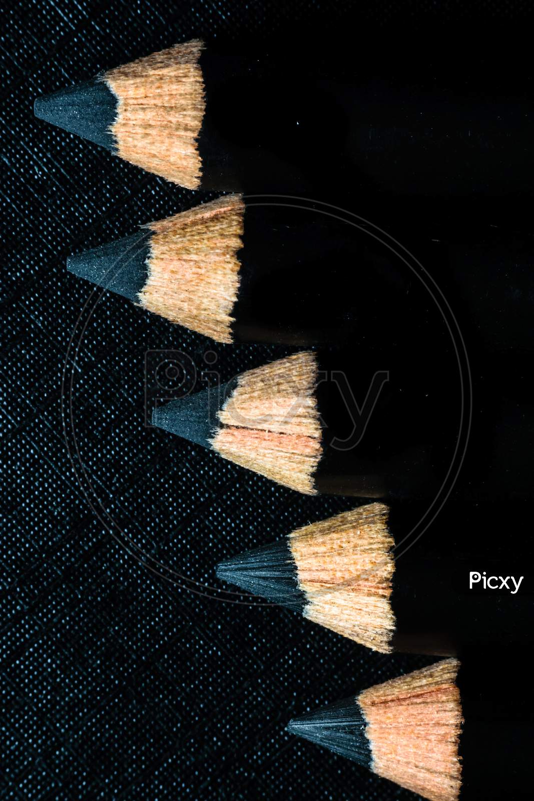 A Group Of Pencils Are Kept On A Dark Paper In Ascending Order
