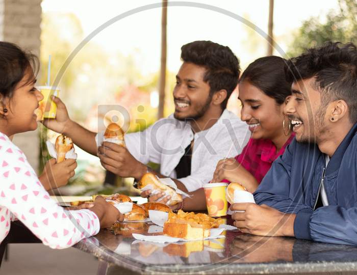 A Group of Happy Young People talking to each other While having their Food