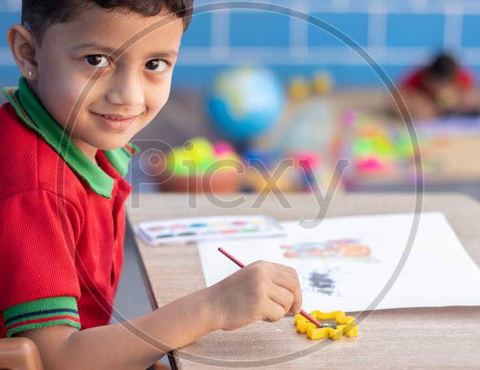 A Kid in School dress is Busy In Drawing or Painting At School