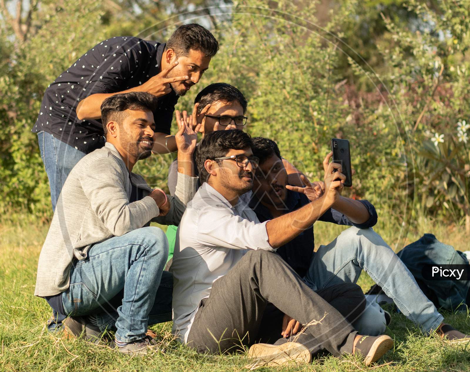 Group Of Friends Taking A Self Portrait In The Park - Concept Of Young People Addicted To Selfie - Three Friends Are Sitting On Bench In Park And Taking Selfie At Park