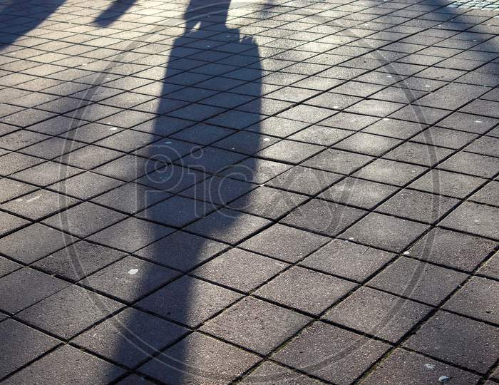 Shadows Of People In A European Shopping Area On A Cobblestone Ground