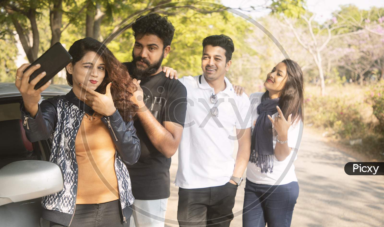 A Group of Happy Young People taking a Selfie using Mobile Phone or Smartphone At Outdoors