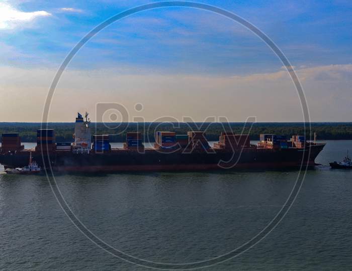 Container Ship arriving port with tig boats.