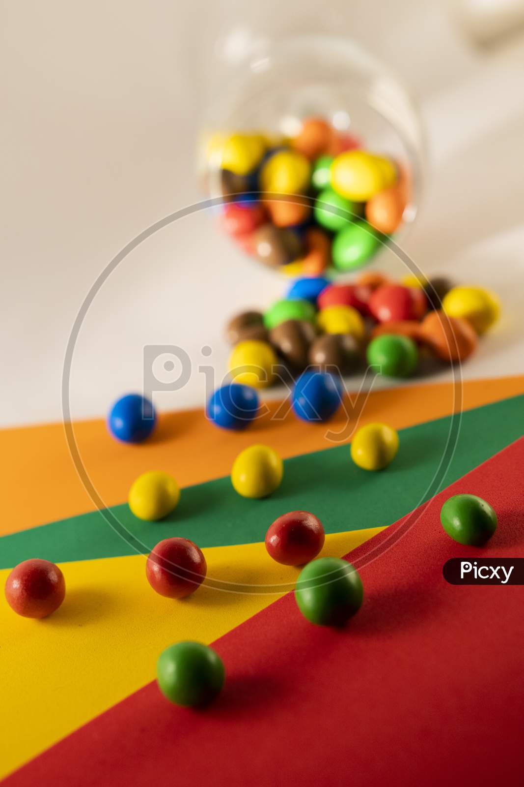 Multi color chocolate candy or candy balls scattered on a multicolored background.