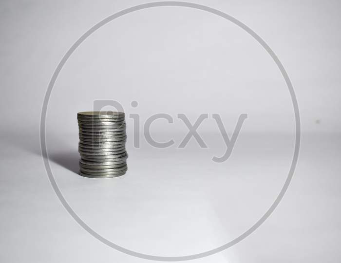 Coins Stacked On Each Other On White Background. Copy Space Available. Selective Focus Image.