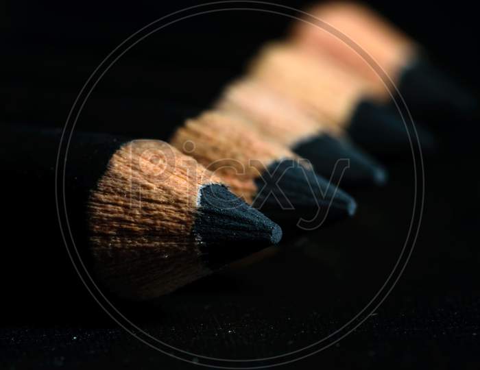 A Group Of Pencils Are Kept On A Dark Paper In Ascending Order. Selective Focus On The Tip Of The Proximal Pencil