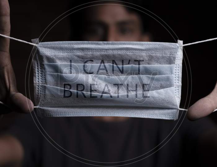 Young Man Holding Medical Mask With I Can'T Breathe Inscription On It. Cooncept Of Protest About Racial Discrimination Of Black People In U.S. America.