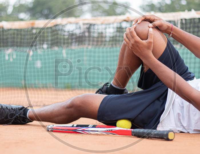 Young Indian Man Holding Knee Due To Pain in a Tennis Court