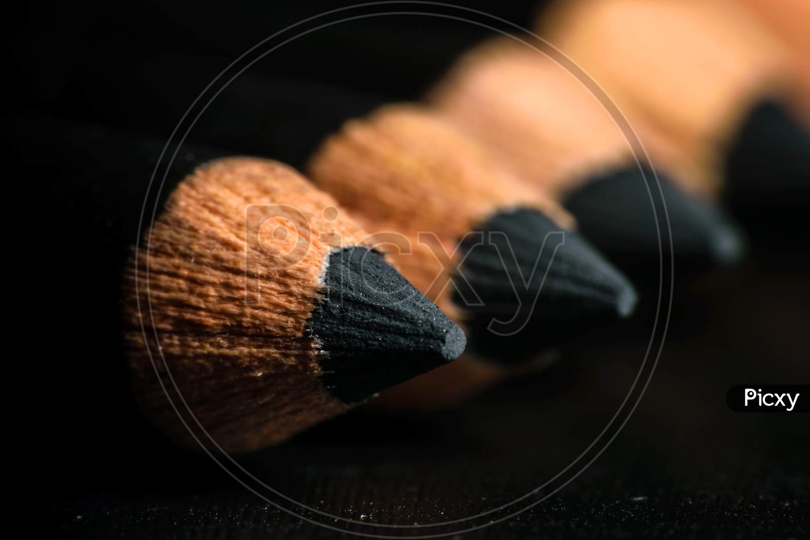 A Group Of Pencils Are Kept On A Dark Paper In Ascending Order. Selective Focus On The Tip Of The Proximal Pencil
