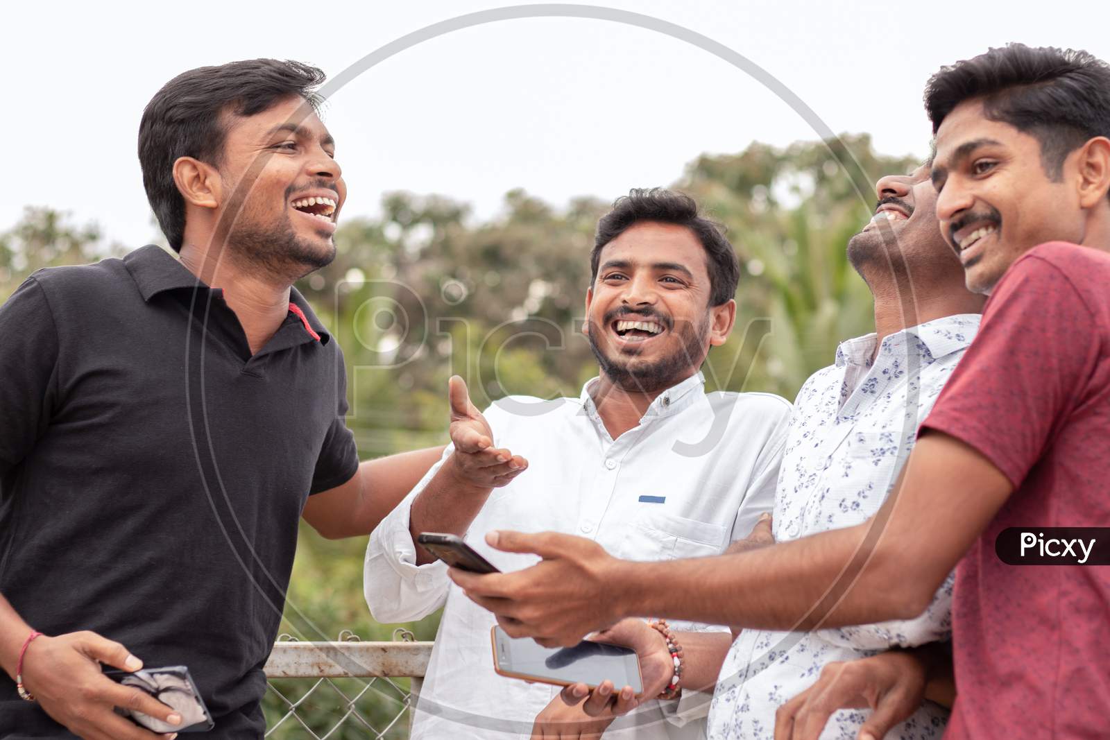 Group Of Happy Young College Students By Looking At Mobile Phone Laughing Loudly