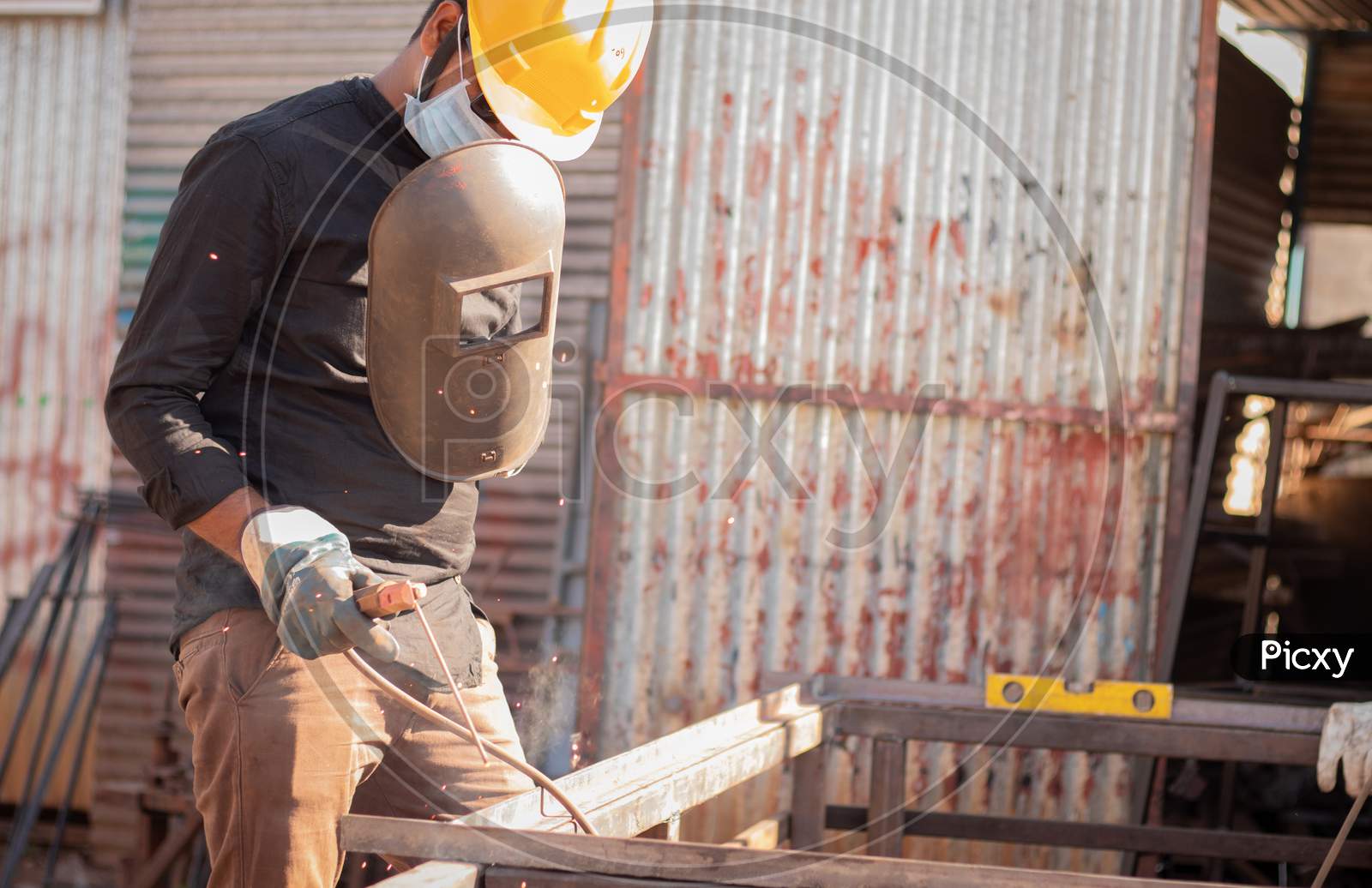A Young Welder doing welding with a Helmet and Mask during Corona Virus Pandemic