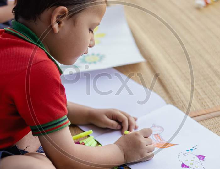 A Kid in School dress is Busy In Drawing or Painting At School