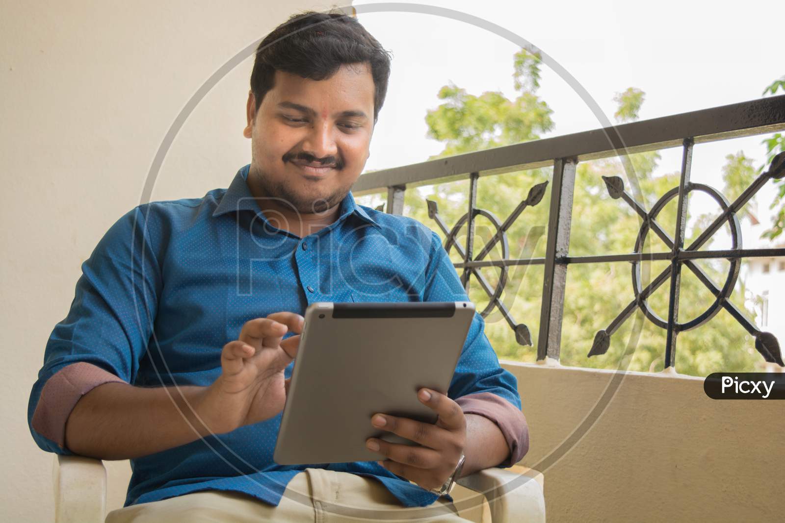 A Happy Young Indian Man Using Tablet Gadget or iPad