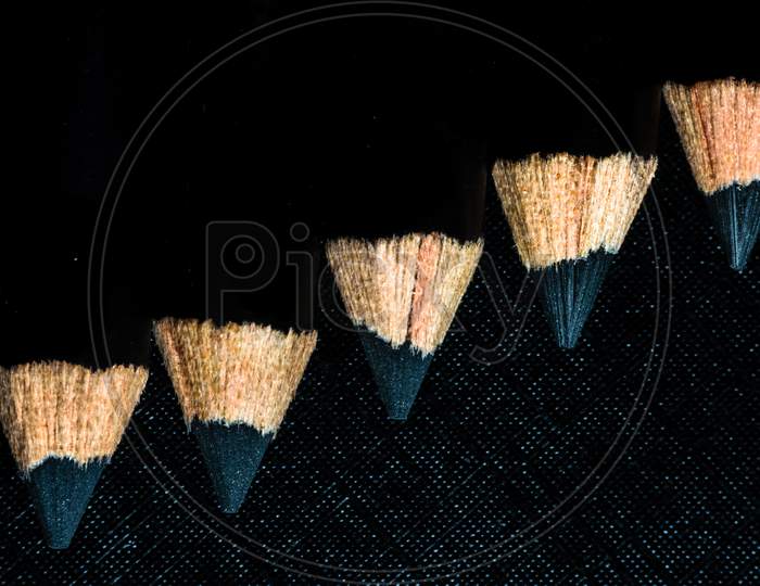 A Group Of Pencils Are Kept On A Dark Paper In Ascending Order. Top View
