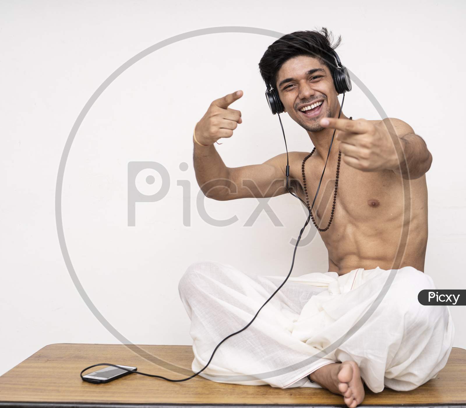 Young Indian Handsome Boy Wearing Dhoti,Listening To Songs On His Headphones, Cheerful And Happy.
