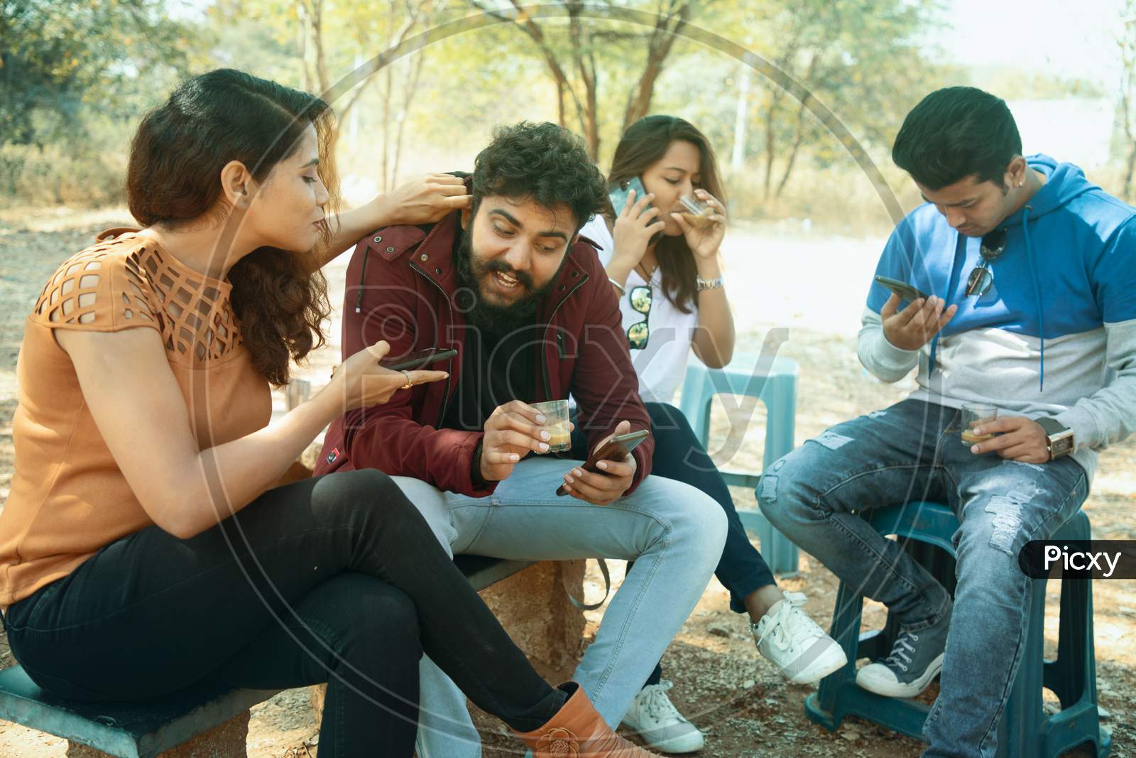 Group of Happy Young People using Smartphone while having Tea