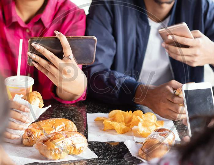 A Group of Young People using Mobile phones or Smartphone While having their Food