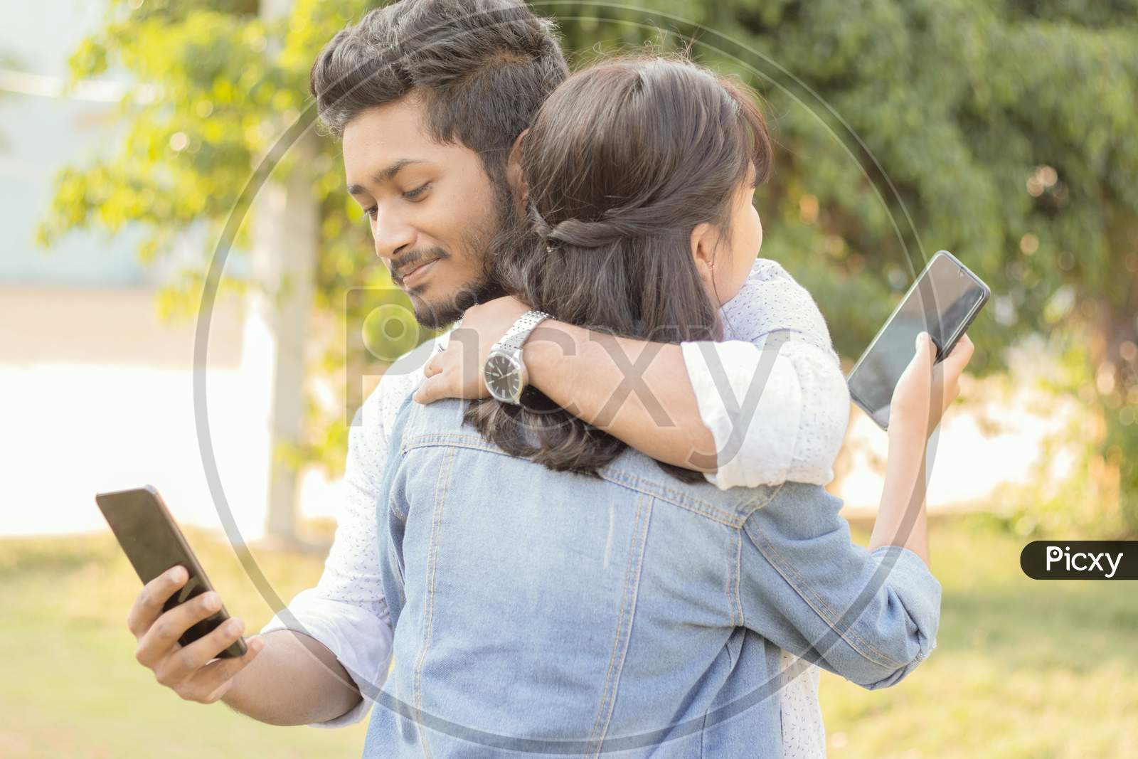 A Couple in Hugged pose using a Smartphone
